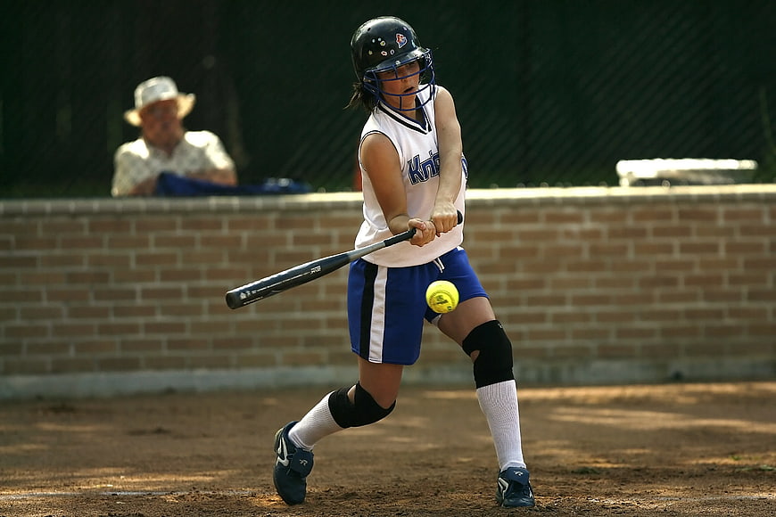 Female softball player hitting ball during game