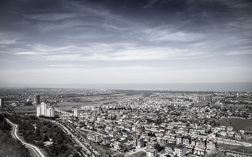 Black and white aerial view of coastal city with winding road