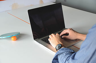 Person typing on laptop at ping pong table workspace