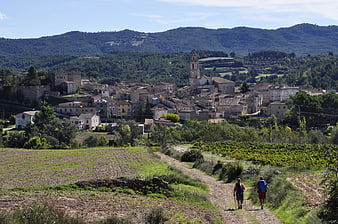 Hikers on rural trail approaching historic Spanish village