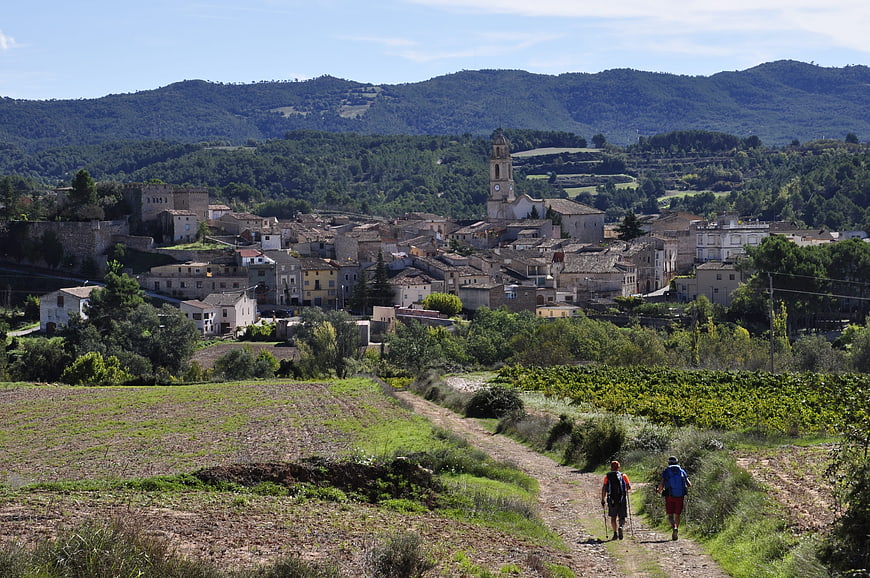 Hikers on rural trail approaching historic Spanish village
