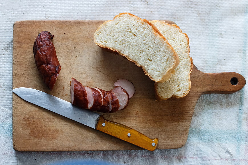 Sliced sausage and bread on wooden cutting board