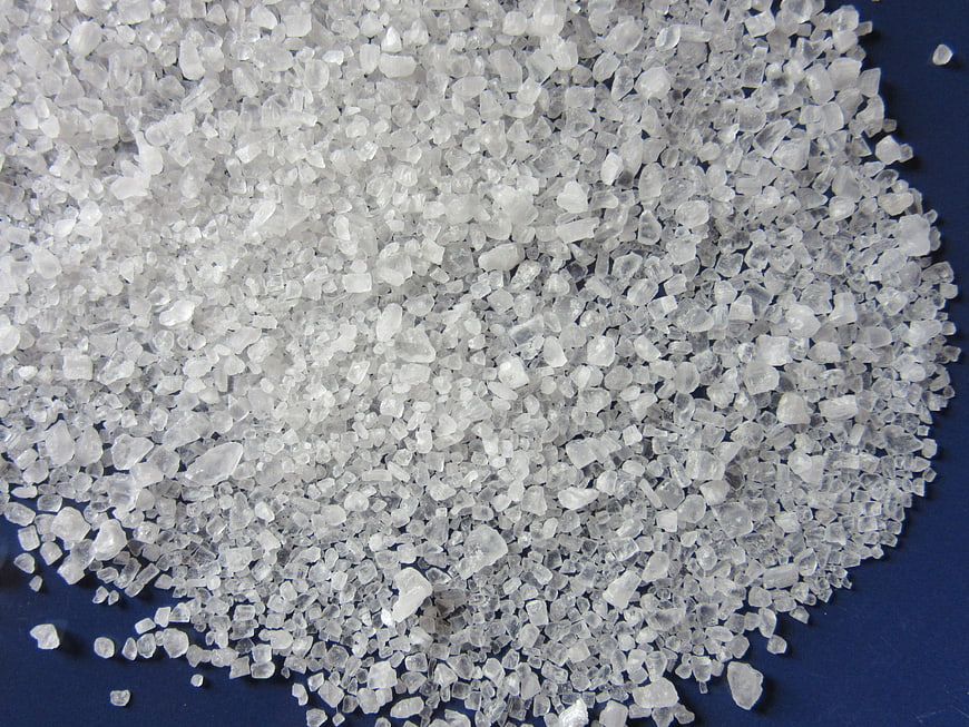 Close-up of white coarse salt crystals on blue background