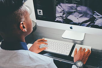 Man working on Apple iMac computer at desk