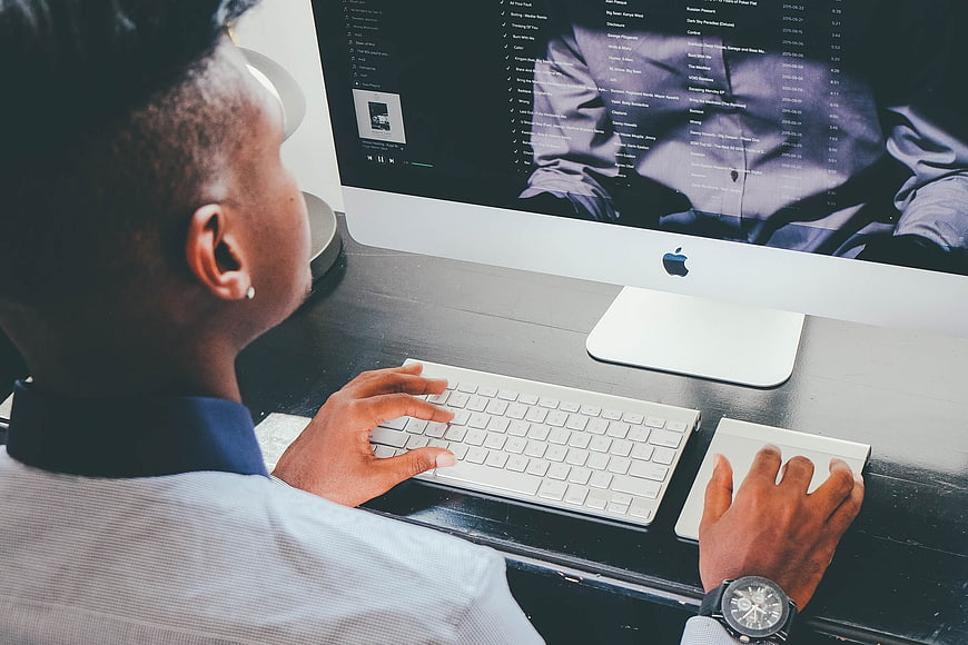 Man working on Apple iMac computer at desk