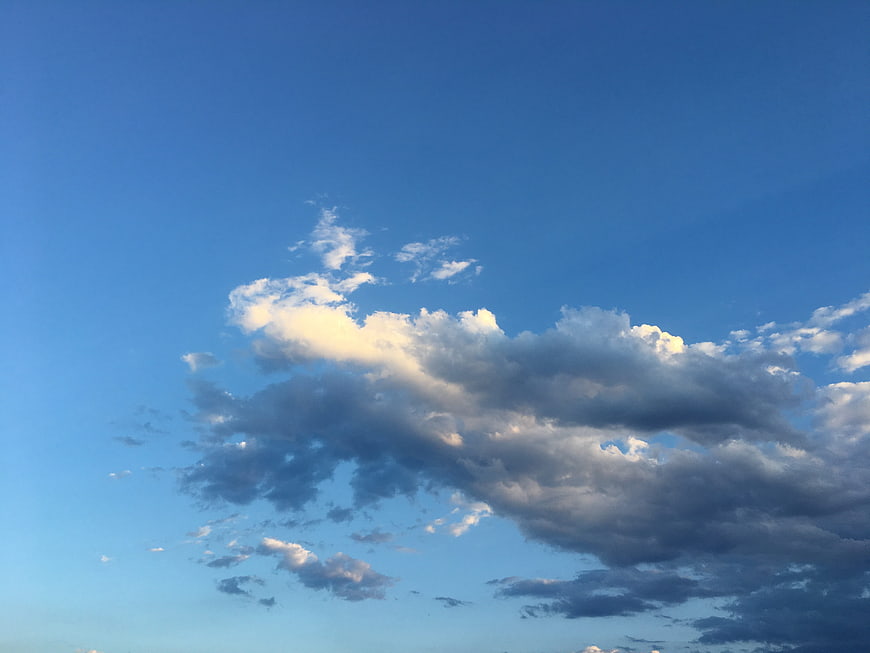 Dramatic white clouds against a clear blue sky background