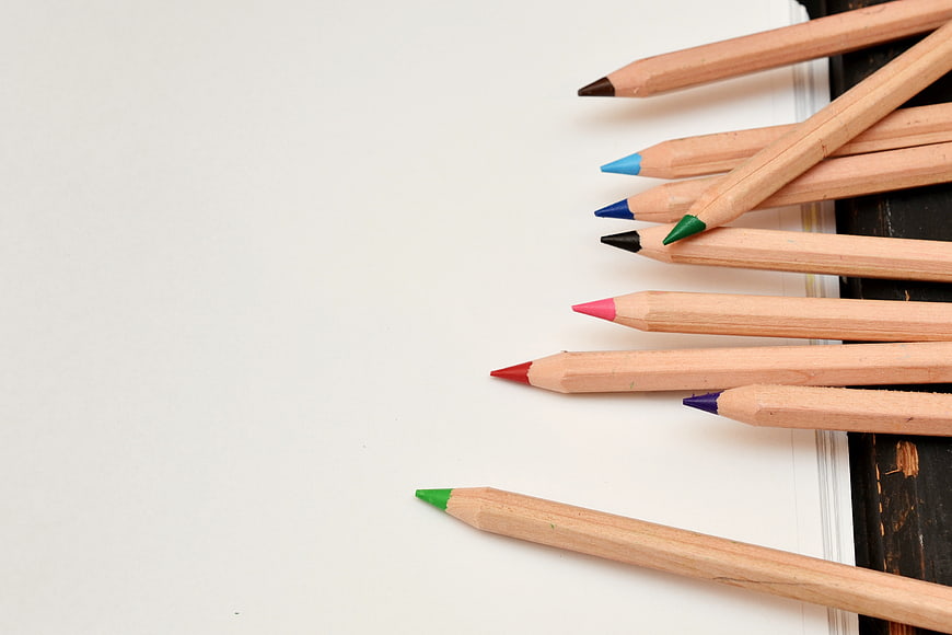 Colorful wooden pencils on white paper with copyspace