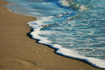 Close-up of ocean waves washing over sandy beach