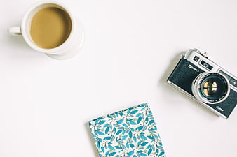 Flat lay of vintage camera, coffee, and floral notebook on white