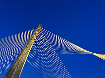 Low angle view of cable-stayed bridge tower against blue sky