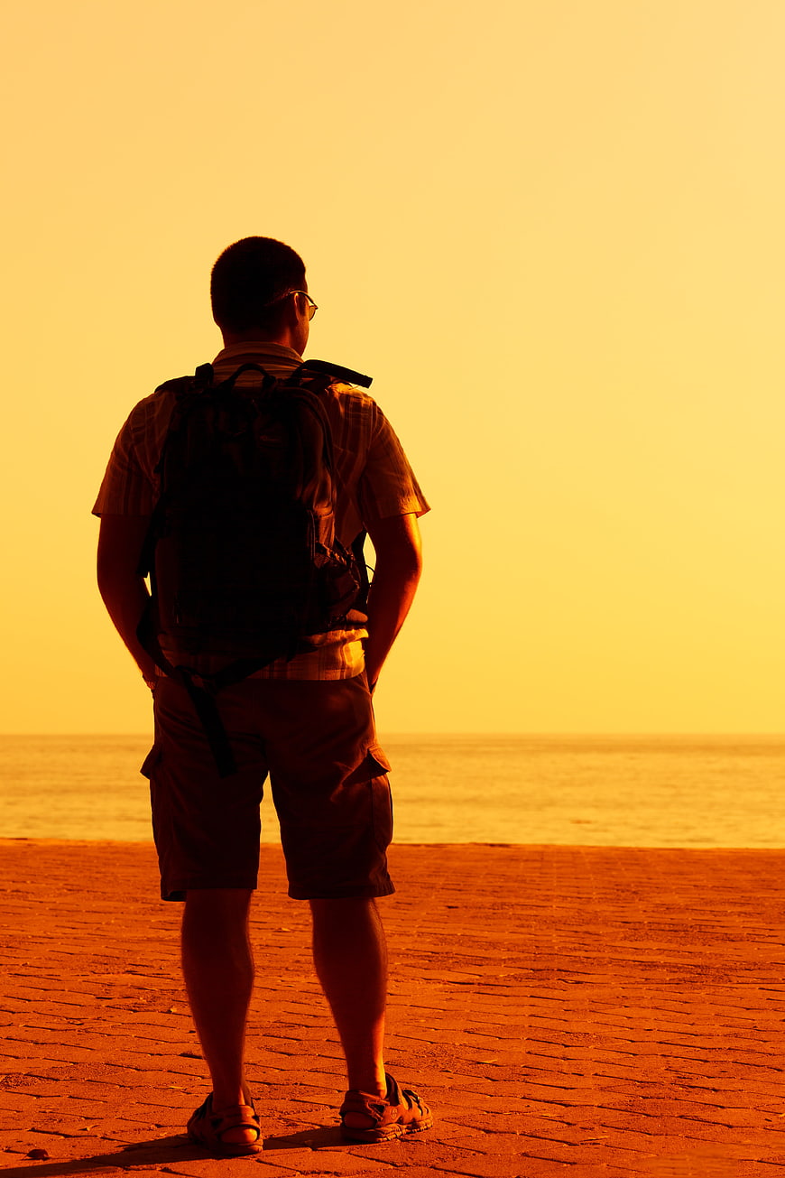 Silhouette of Man with Backpack Watching Sunset at Beach