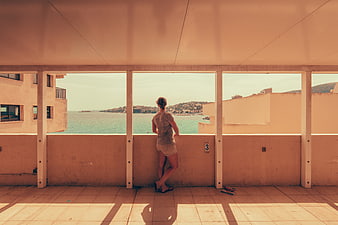 Woman Looking Out at Coastal View from Balcony