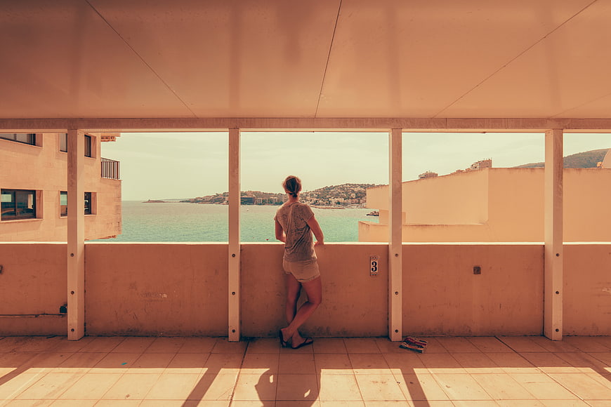 Woman Looking Out at Coastal View from Balcony