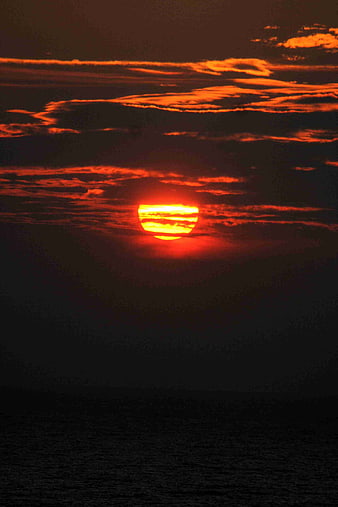 Dramatic Red Sunset Over Dark Ocean With Clouds