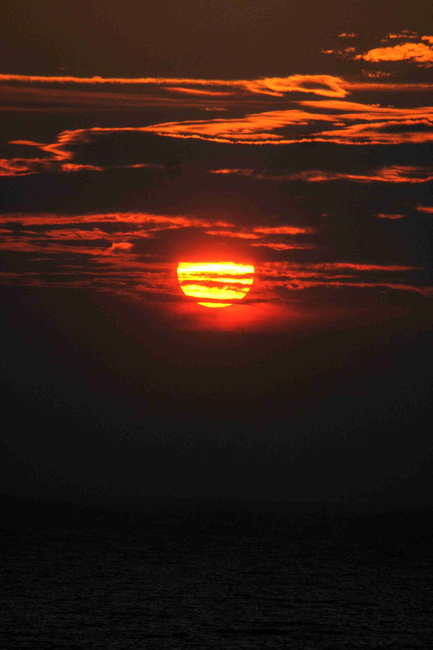 Dramatic Red Sunset Over Dark Ocean With Clouds