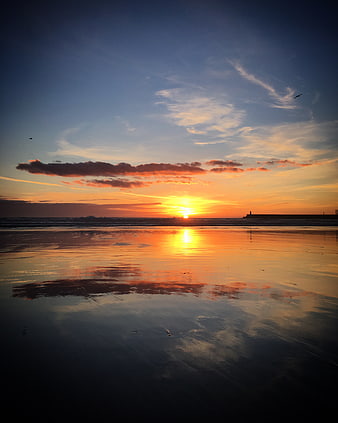 Serene Sunset Reflection on Wet Sandy Beach