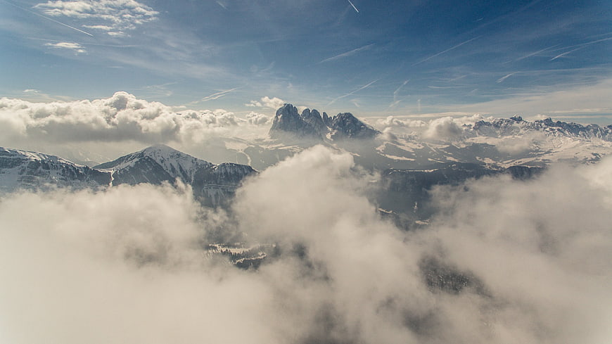 Aerial View of Snowy Dolomites Peaks Above Clouds