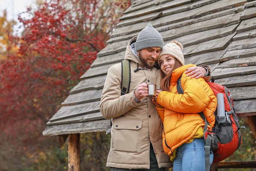 Happy Couple Hiking in Autumn with Backpacks and Coffee
