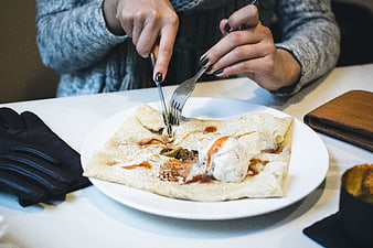 Woman eating crepe with ice cream and caramel