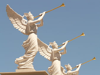 White Angel Statues with Golden Trumpets Against Blue Sky