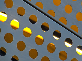 Abstract Perforated Metal Facade with Golden Sunlight
