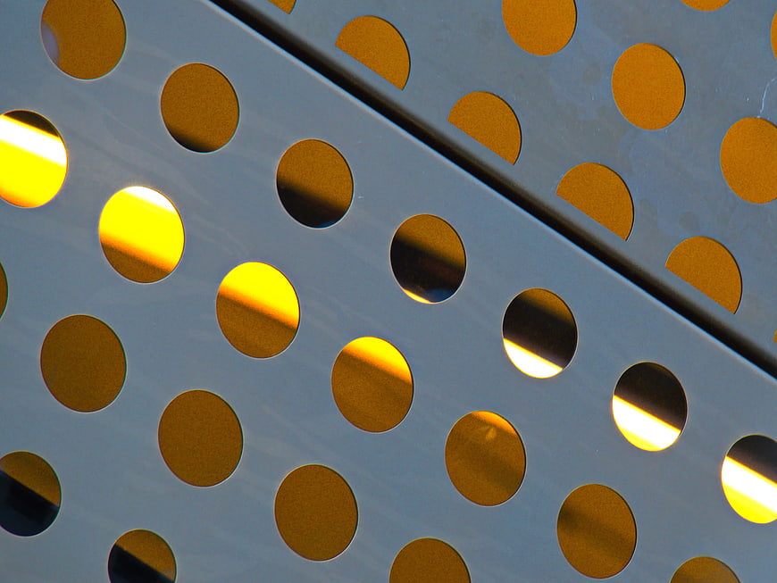 Abstract Perforated Metal Facade with Golden Sunlight