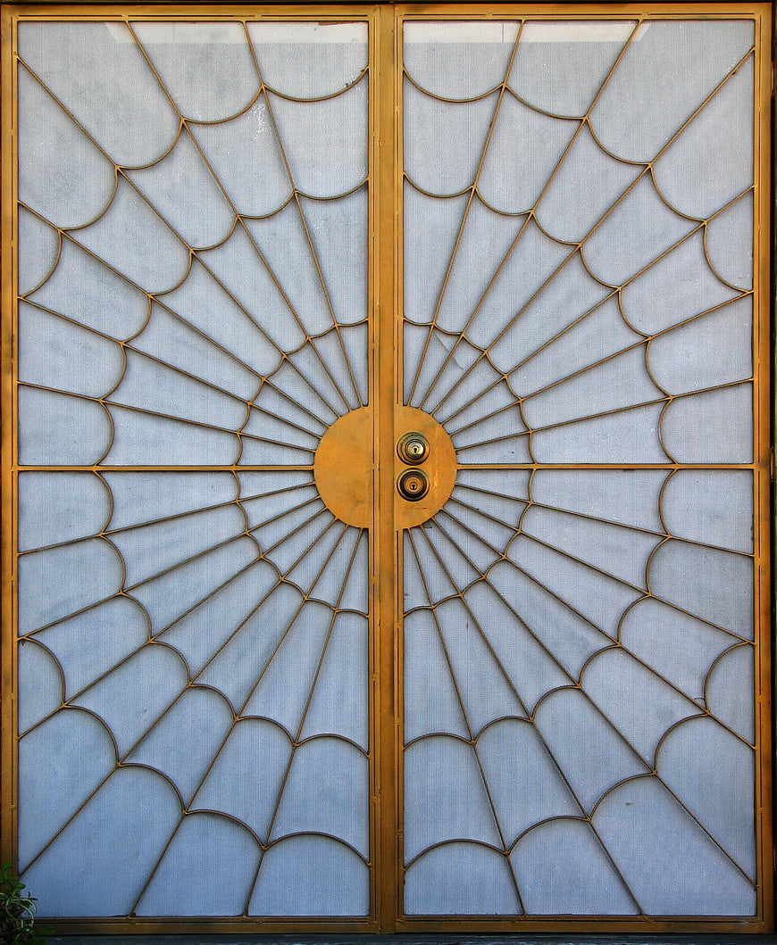 Golden metal door with intricate spiderweb radial design