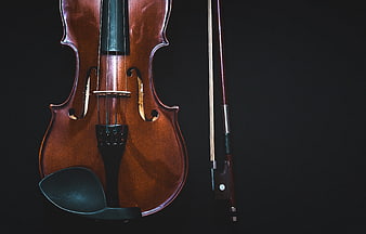 Close-up of a wooden violin and bow on a black background