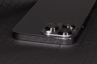 Close-up of black smartphone camera module on textured surface