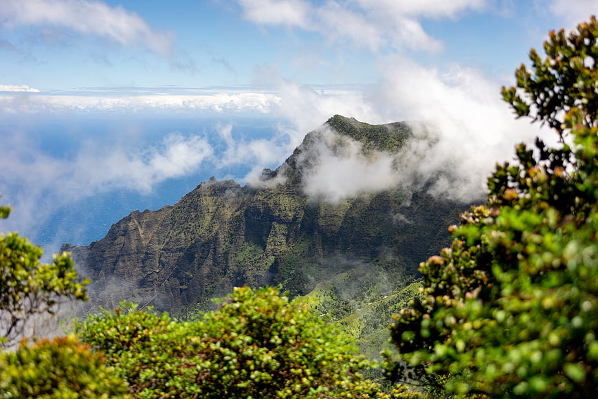 Majestic Mountain Peak Above Clouds with Lush Green Foreground