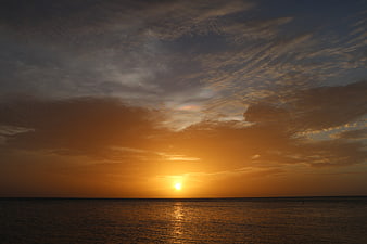 Golden Sunset Over Calm Ocean with Dramatic Clouds