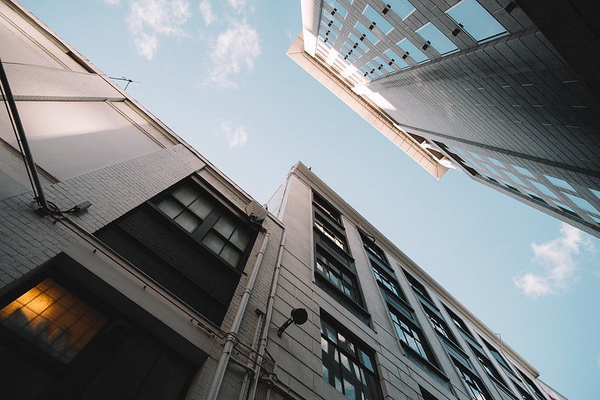 Low angle view of modern city buildings against blue sky