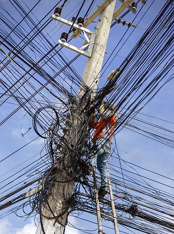 Electrician climbing utility pole tangled with chaotic wires