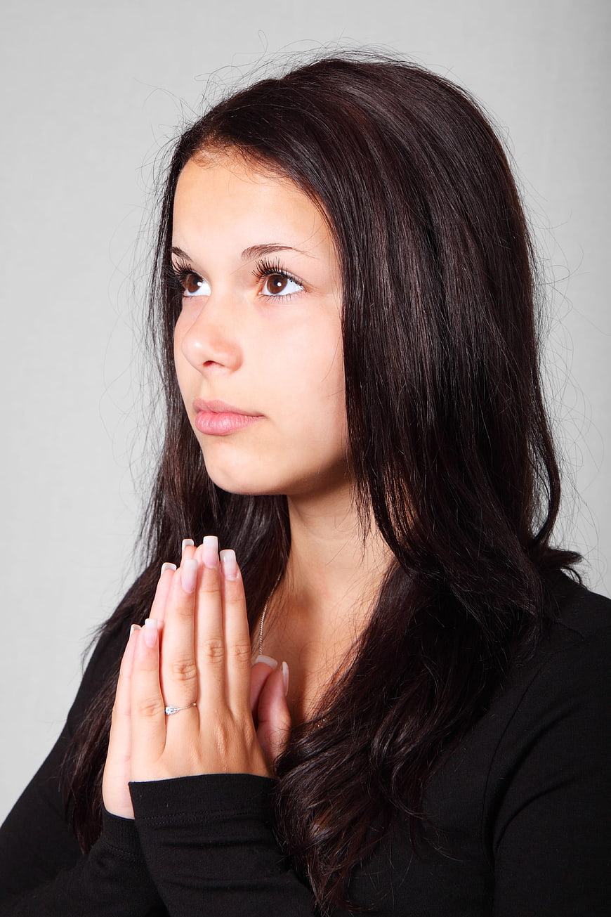 Young Woman Praying with Hands Together in Portrait