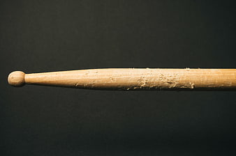 Close-up of worn wooden drumstick on dark background