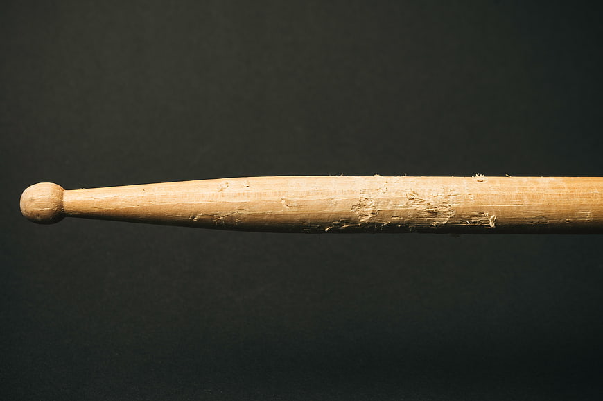 Close-up of worn wooden drumstick on dark background