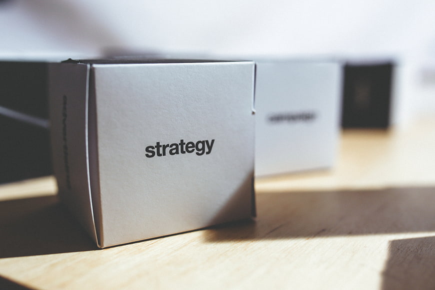 White box labeled strategy on wooden desk