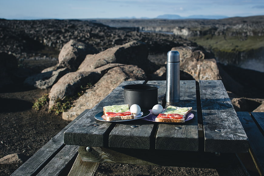 Camping breakfast on wooden table with scenic landscape background