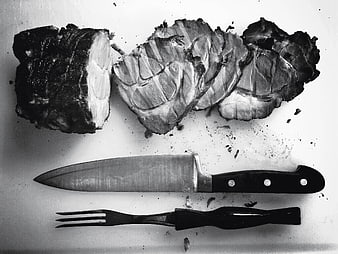Sliced roast beef with knife and fork on cutting board