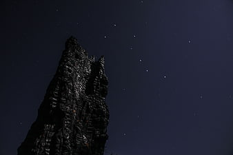 Dark jagged rock formation silhouette against starry night sky