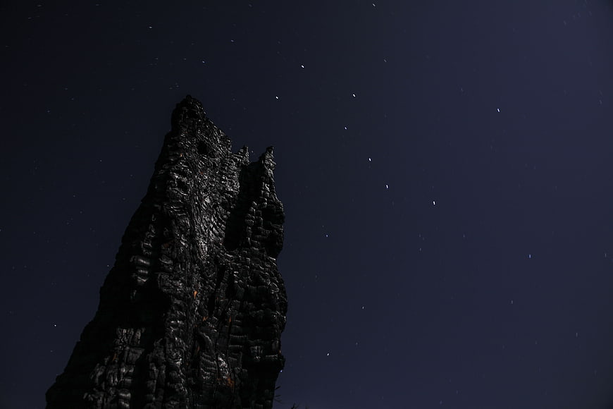Dark jagged rock formation silhouette against starry night sky