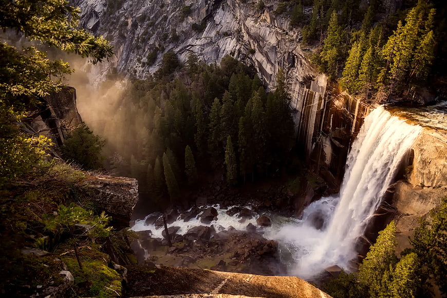 Majestic waterfall cascading down granite cliffs in a forested canyon