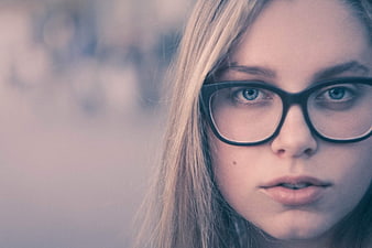 Close-up portrait of blonde woman with glasses looking at camera