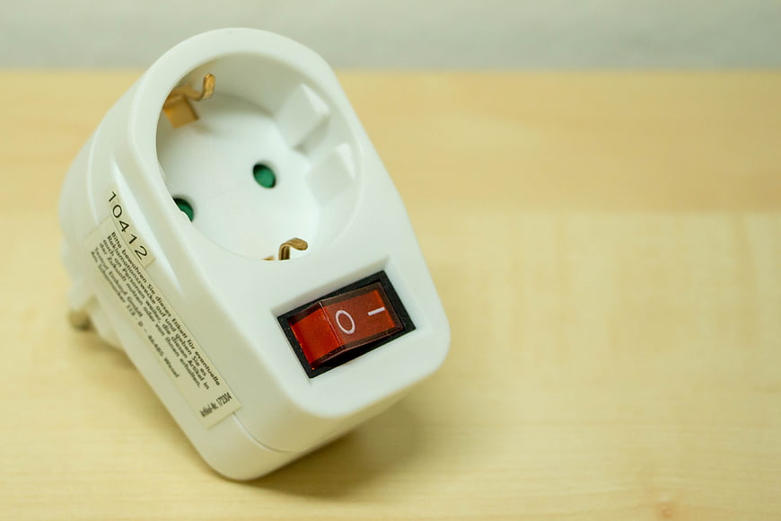 White Travel Adapter With Red Switch On Wooden Surface