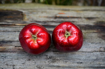 Two Fresh Red Apples on Weathered Wooden Surface