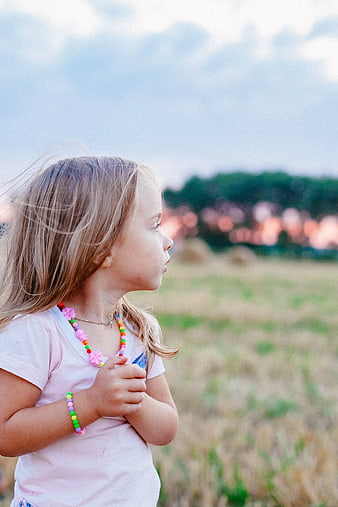 Young Girl in Pink Shirt Looking at Sunset in Field