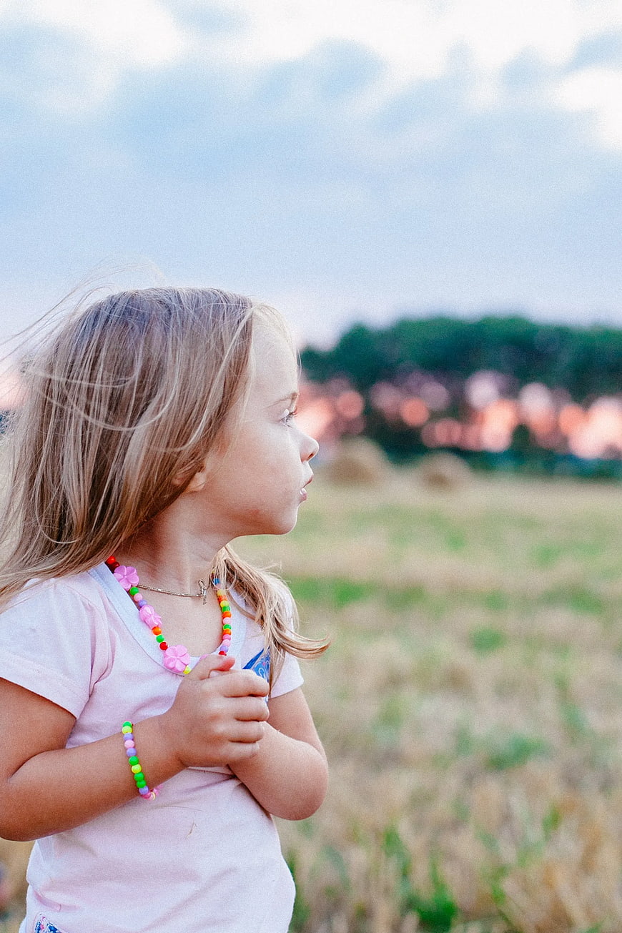 Young Girl in Pink Shirt Looking at Sunset in Field