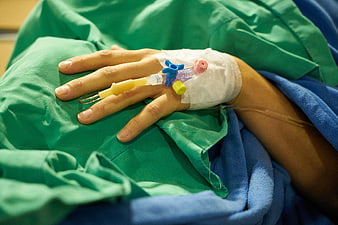 Patient Hand with IV Drip in Hospital Bed