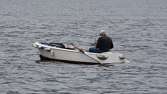 Lone fisherman in small white boat on calm sea