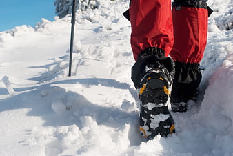 Hiker boots in deep snow with trekking pole